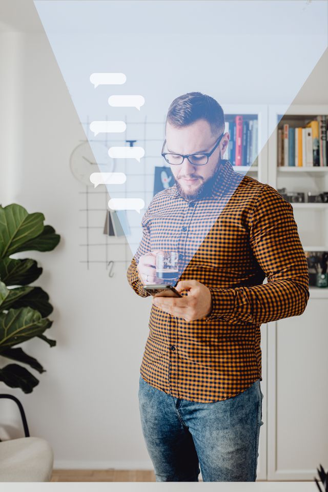 A man in casual attire using a smartphone, standing in a modern home office with overlay graphics.